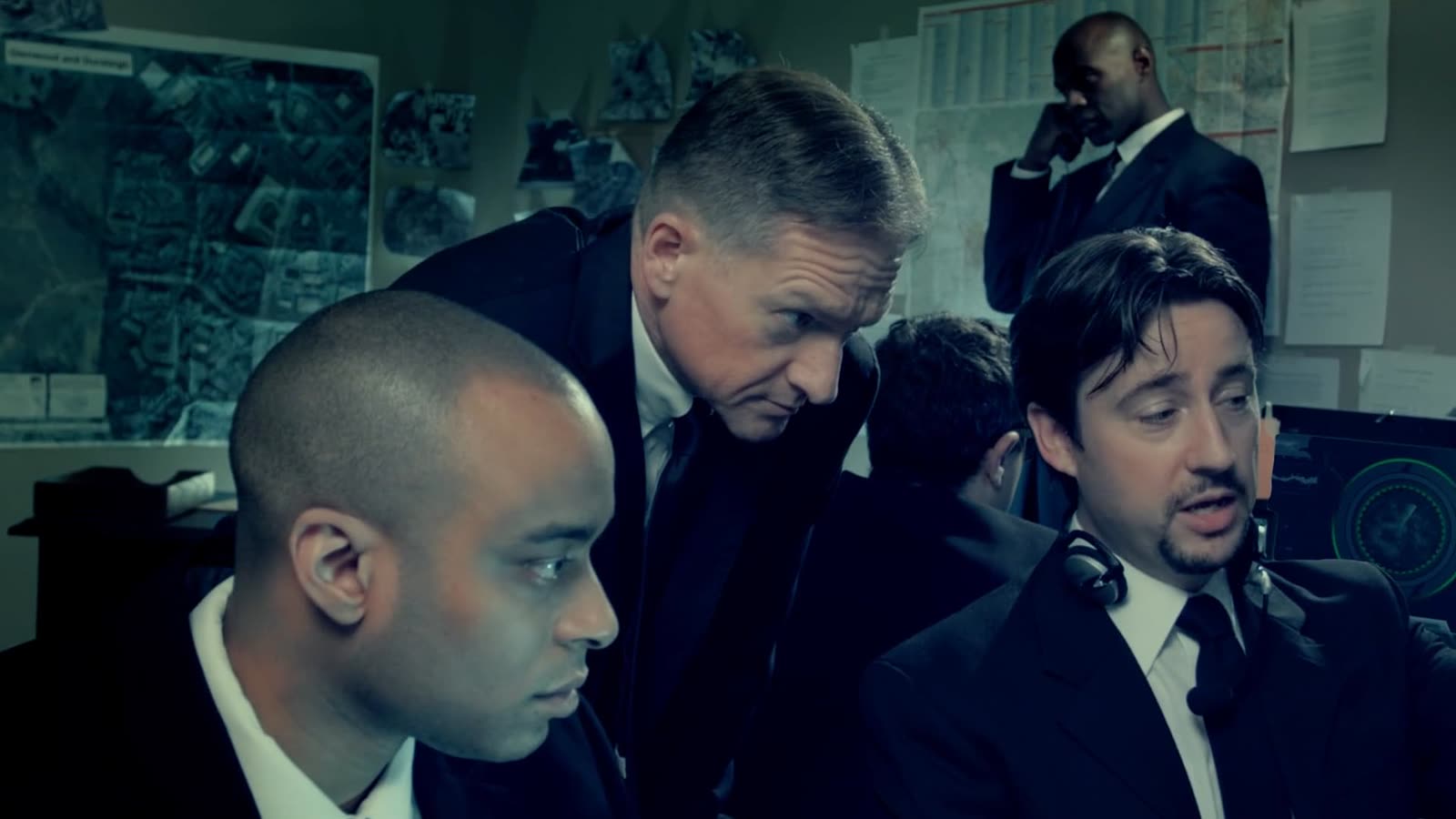 Agents gathered around a monitor in a scene from Harker: The Awakening