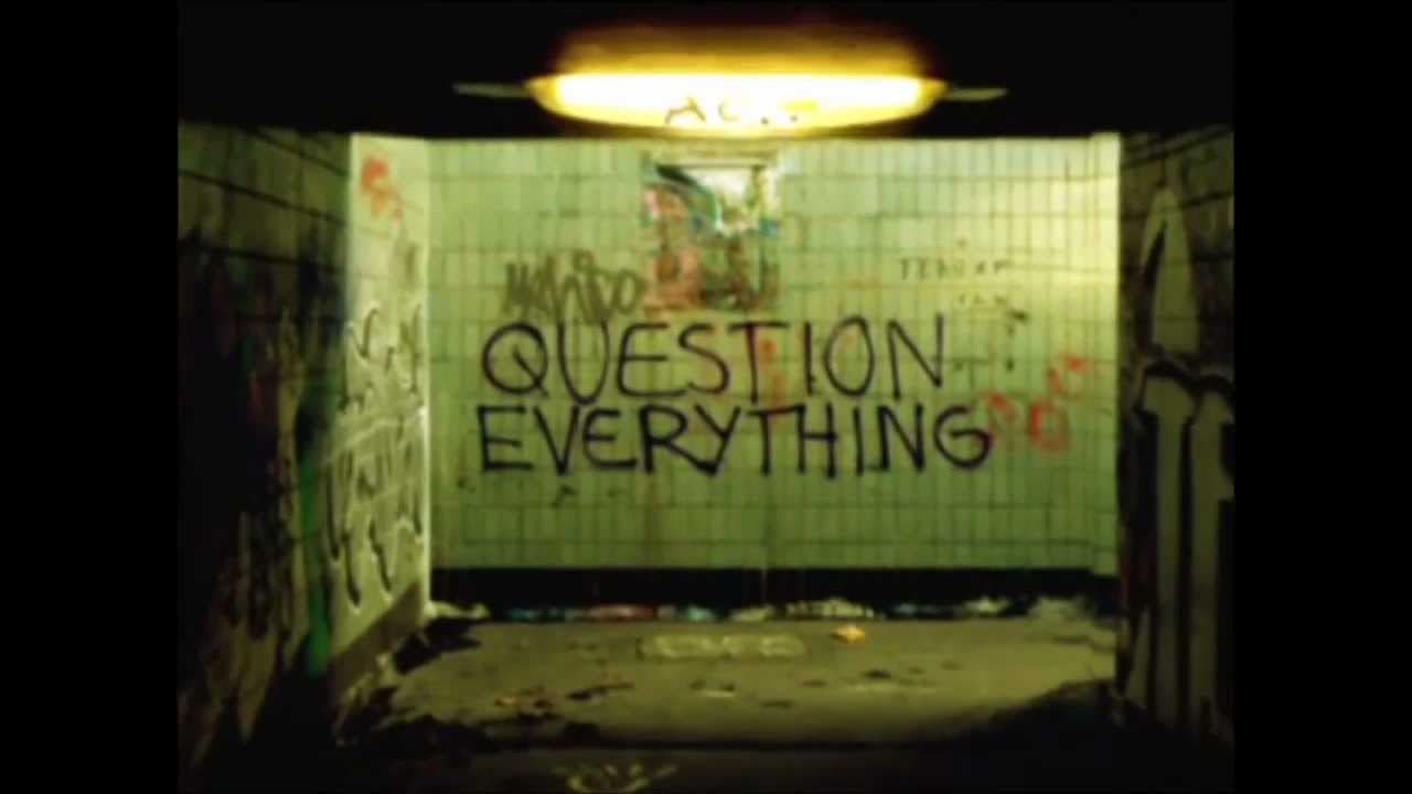 Graffiti reading Question Everything in a tiled tunnel